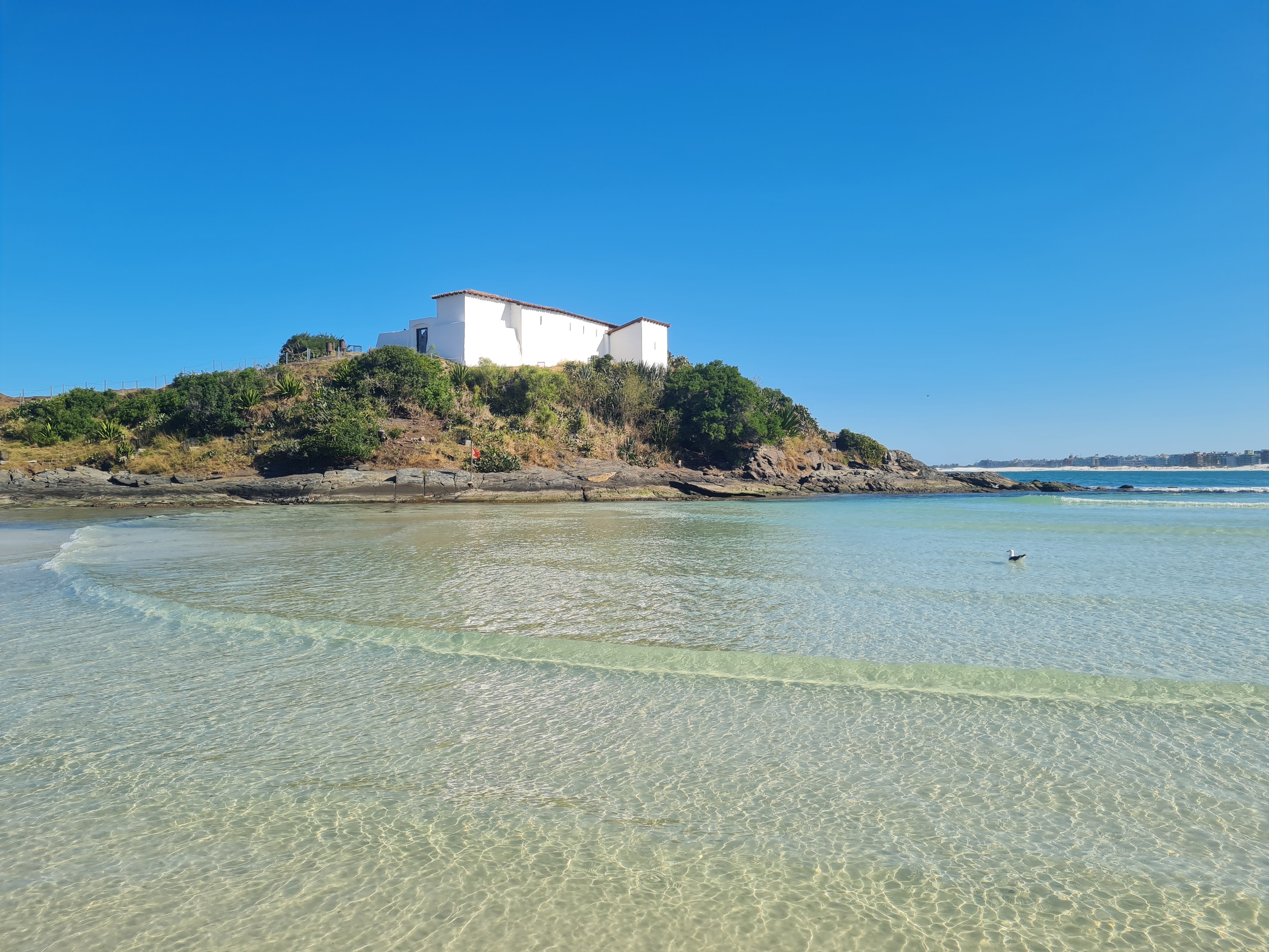 Praia do Forte em Cabo Frio, com o Forte de São Mateus ao fundo e mar cristalino em primeiro plano