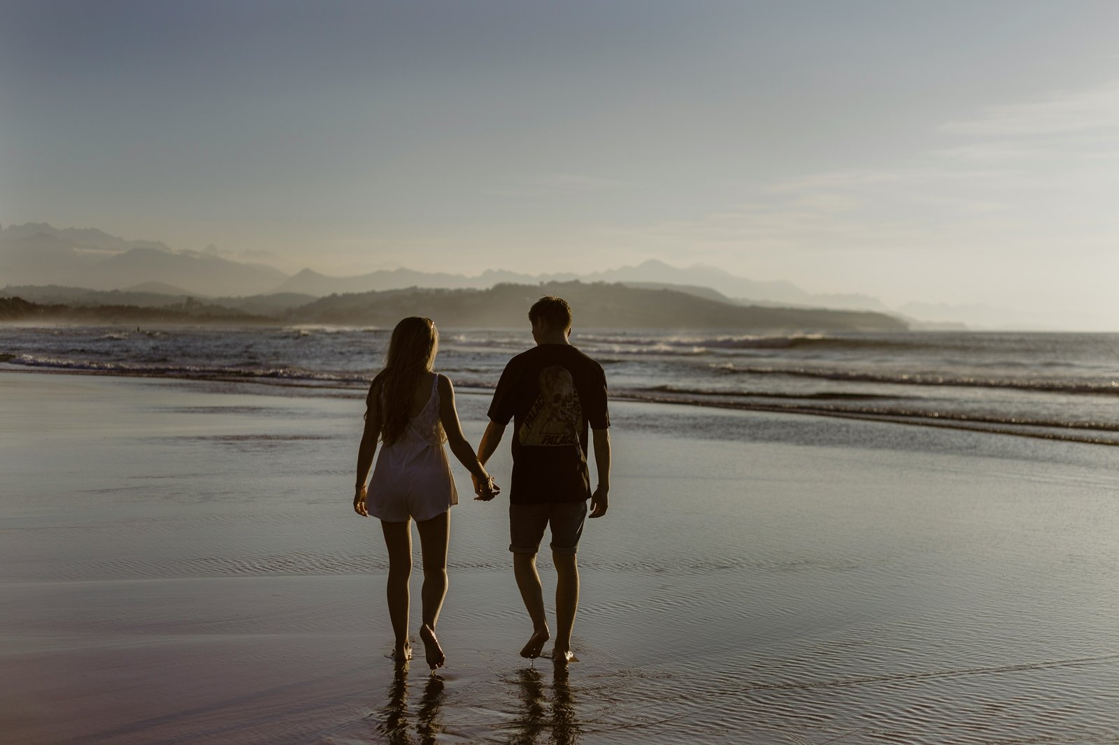 Casal caminhando de mãos dadas na praia