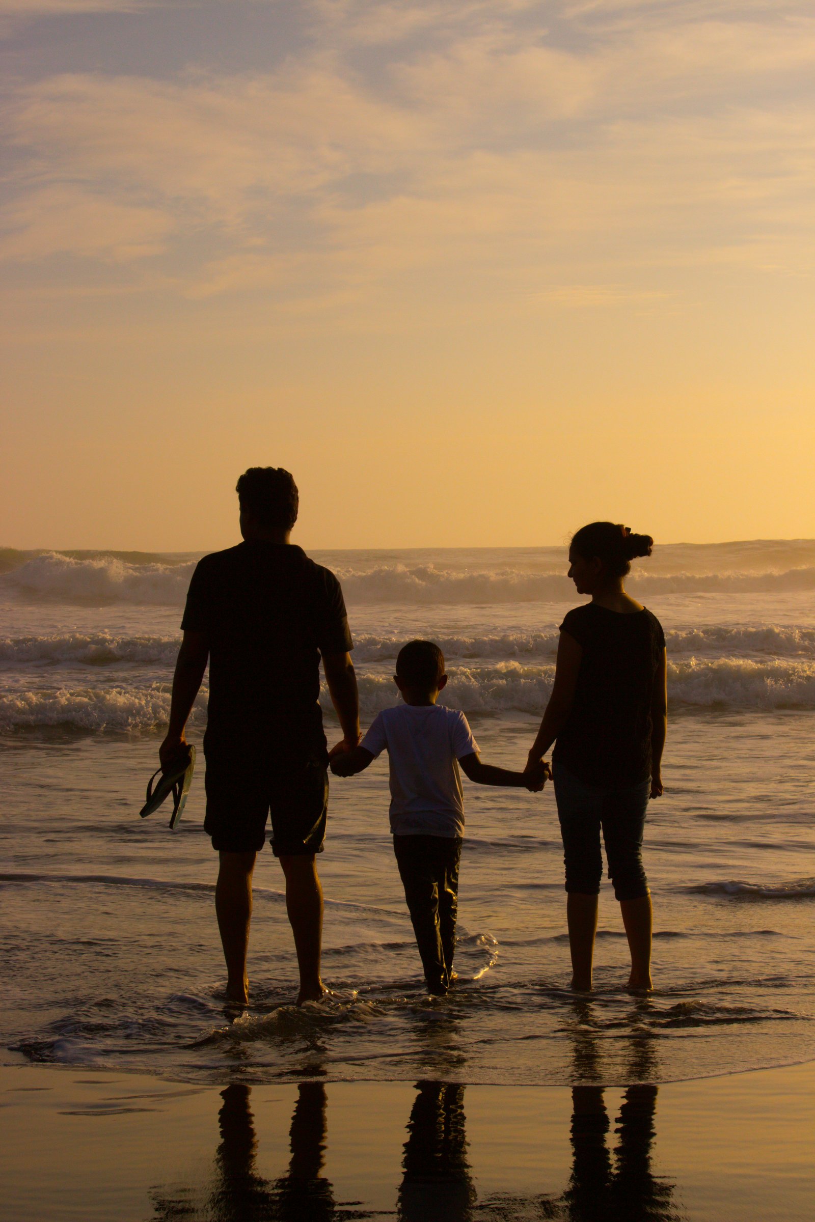 Família silhueta no pôr do sol à beira-mar
