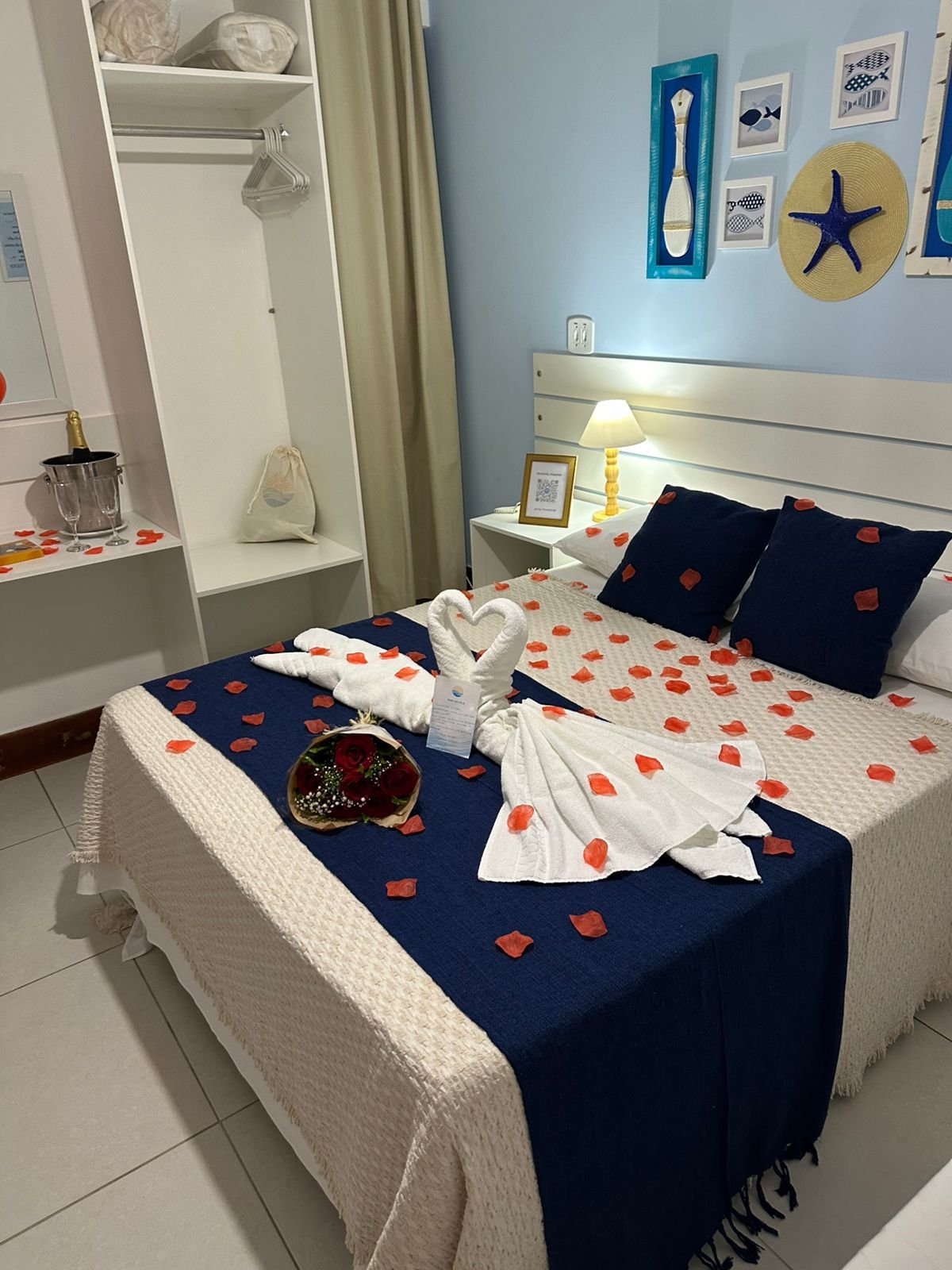 Quarto romântico da Pousada Mar da Vila com decoração de cisnes em toalha, pétalas de rosa e balde de champagne