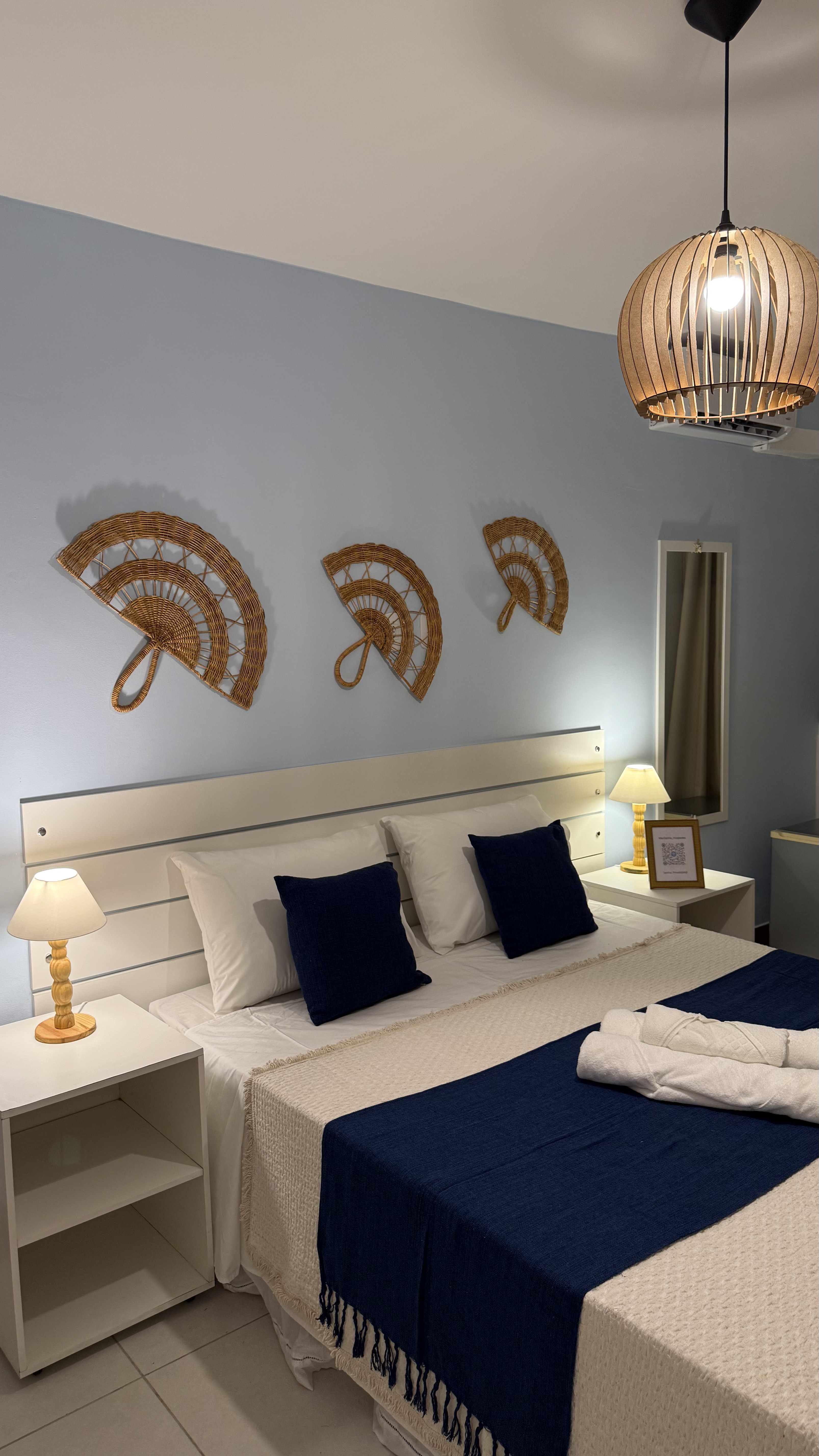 Quarto Triplo Superior com decoração elegante, parede azul claro e abajures dourados